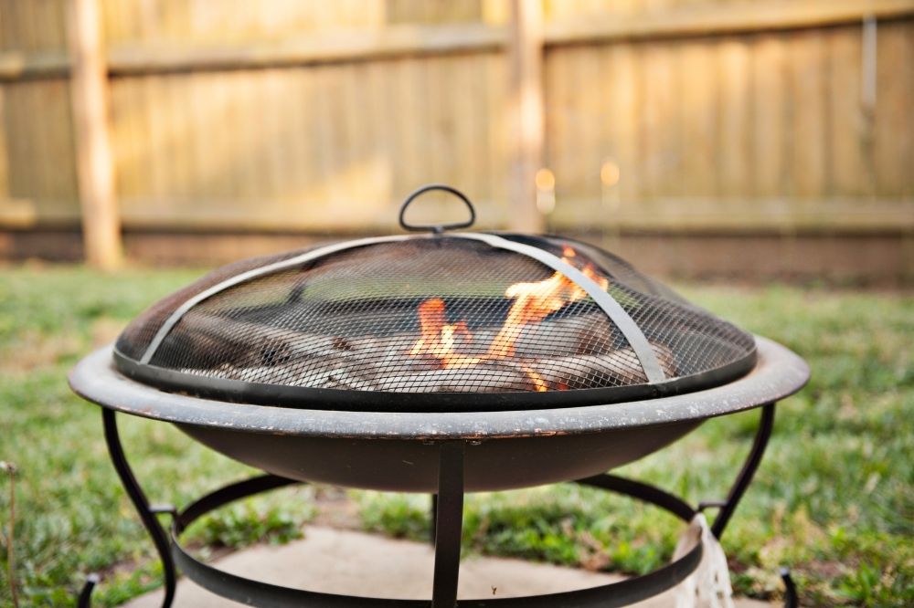 Small fire bowl with a spark arrestor in a backyard.